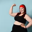 fatty-ginger-lady-red-headband-black-top-leggings-fitness-bracelet-showing-her-muscles-smiling-blue-background-fatty-ginger-179927939.jpg